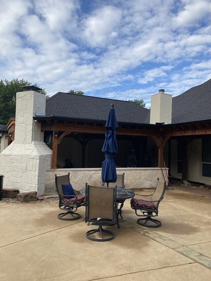 Outdoor kitchen with fireplace by Texstone Homes